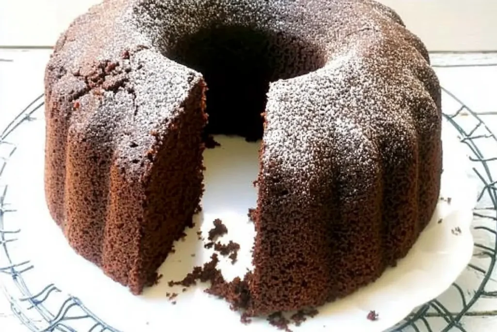 A whole chocolate pound cake recipe on a wooden cake stand, garnished with fresh berries, rustic kitchen setting, warm lighting --ar 3:2 --style raw