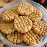 Ingredients for a peanut butter cookie recipe laid out on a wooden surface.